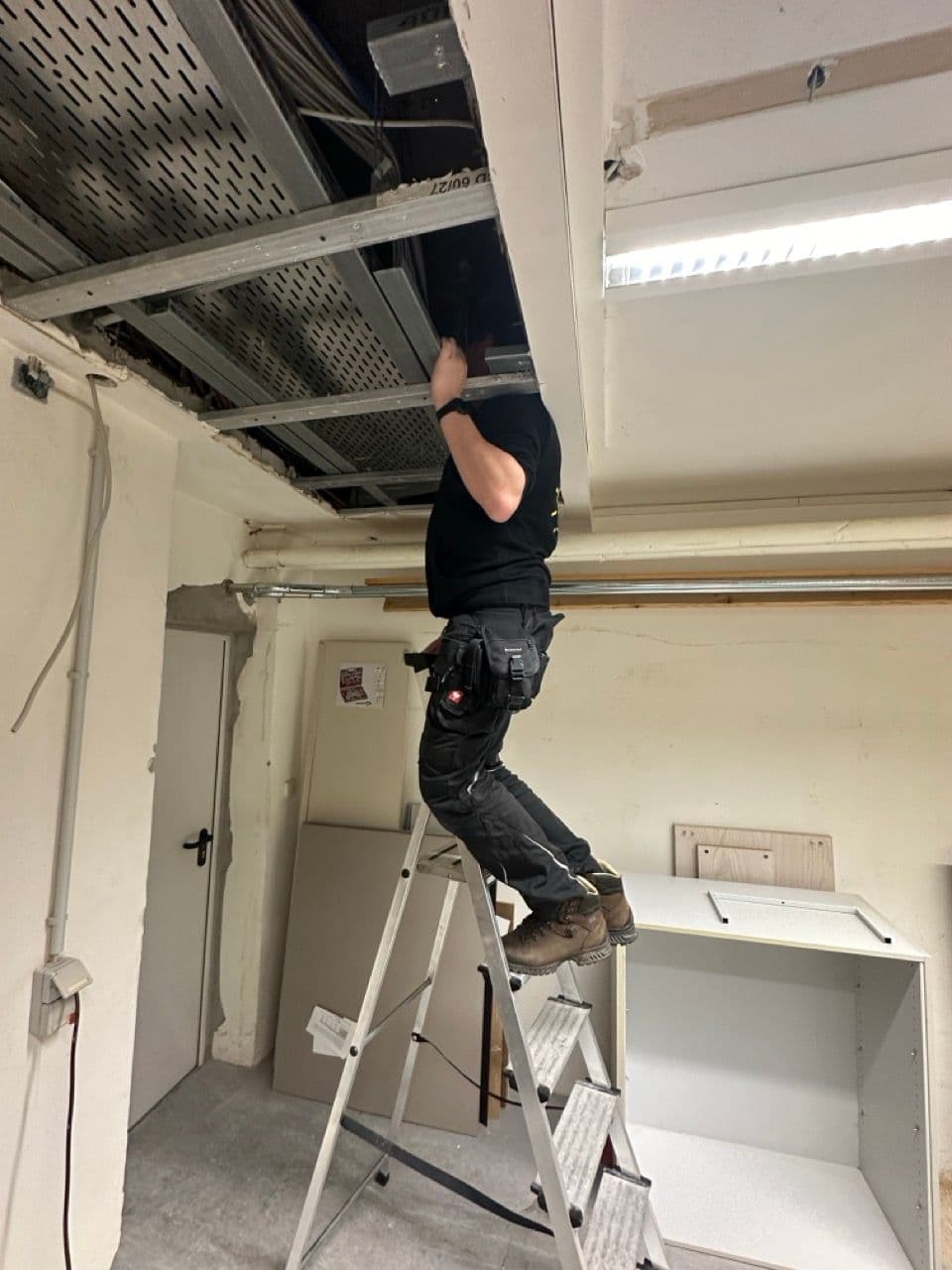 Ein Elektriker der Firma sunday solar überprüft die Leitungen in der Decke der Akademie der Wissenschaften in Berlin