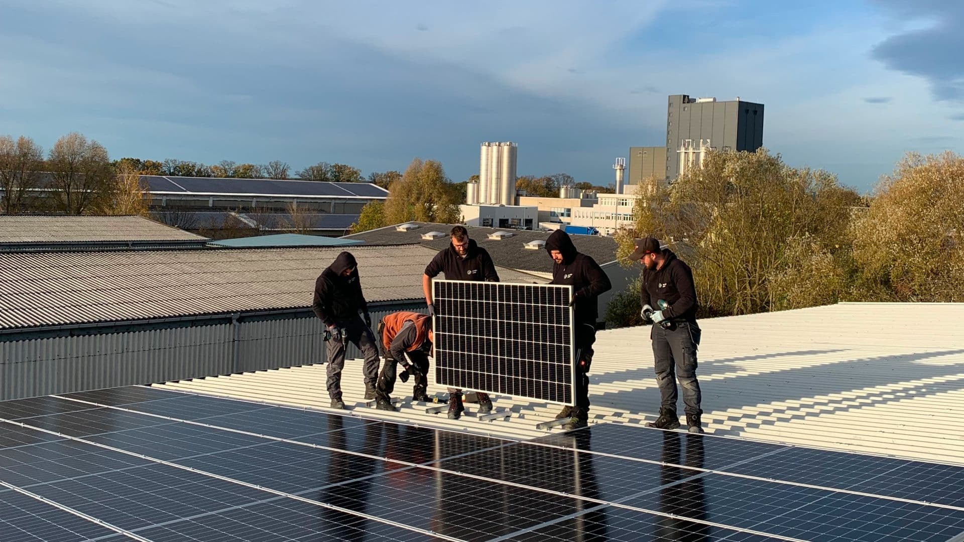 Mitarbeiter von sunday solar stehen auf dem Dach und halten ein Solar-Paneel in den Händen