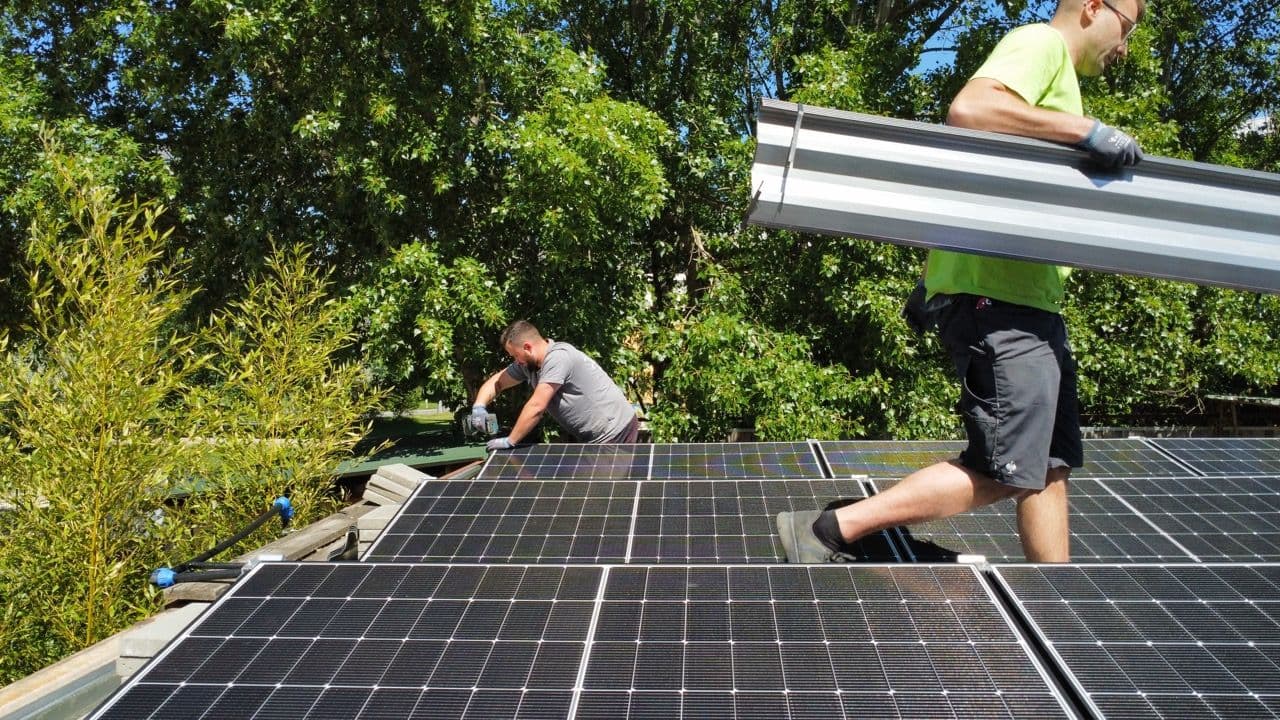 Zwei Mitarbeiter der Solarfirma sunday solar verbauen eine Solaranlage in Berlin